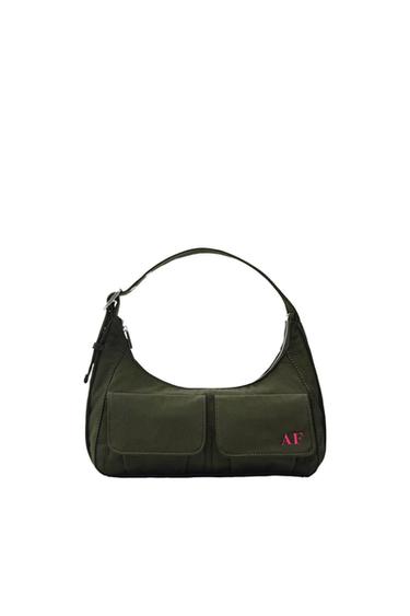 Dark green shoulder bag with a handle and two front pockets. Features the text "AF" in pink. White background.