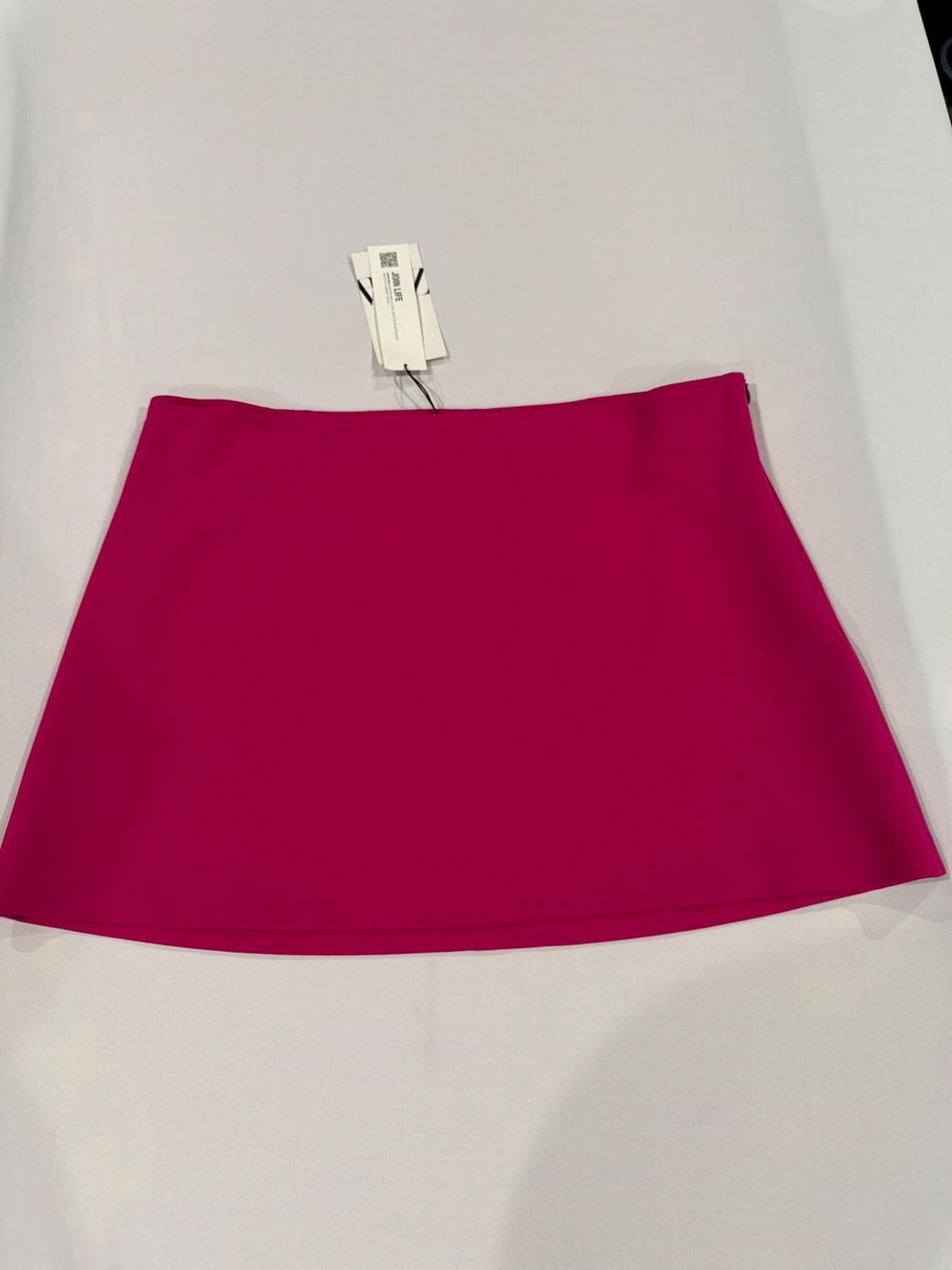 Fuchsia miniskirt on a white surface. At the top, there is a label with the text JOIN LIFE.