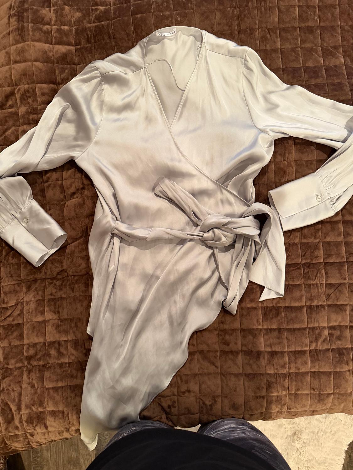 Light gray satin wrap dress with belt, on a quilted brown comforter. Visible neck label.
