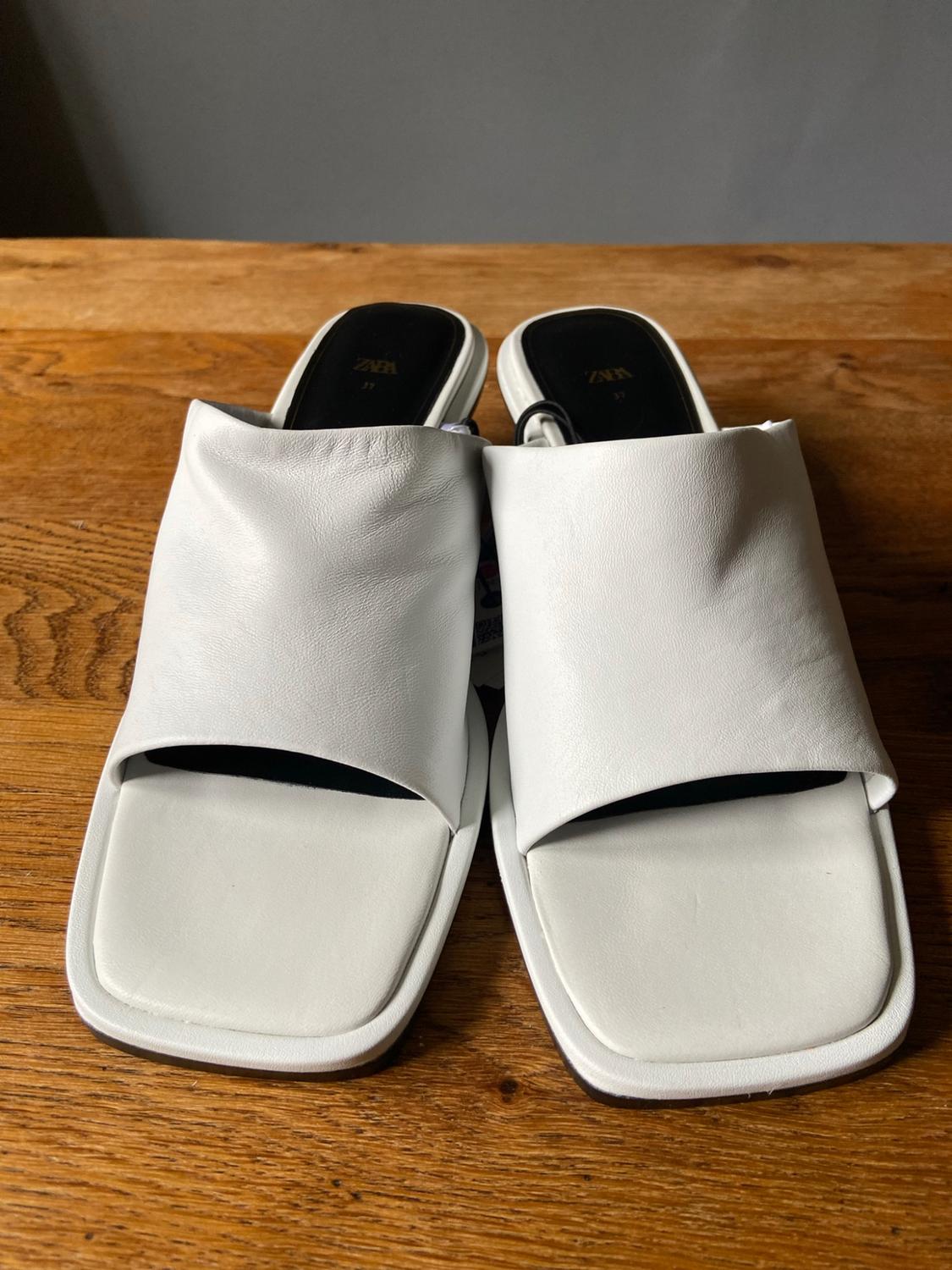 White square-toe sandals with a wide strap on a wooden surface. Black insole with ZARA 37 text.