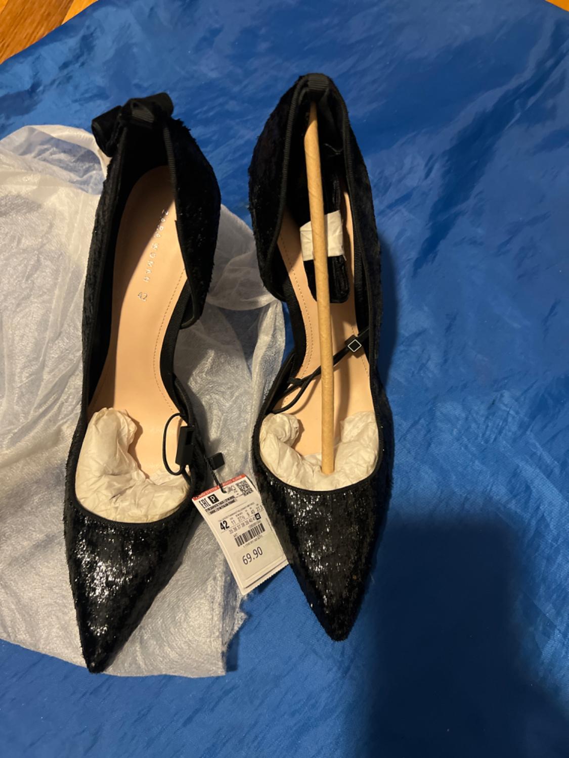 Black sequinned stiletto heels with a back bow, front view.