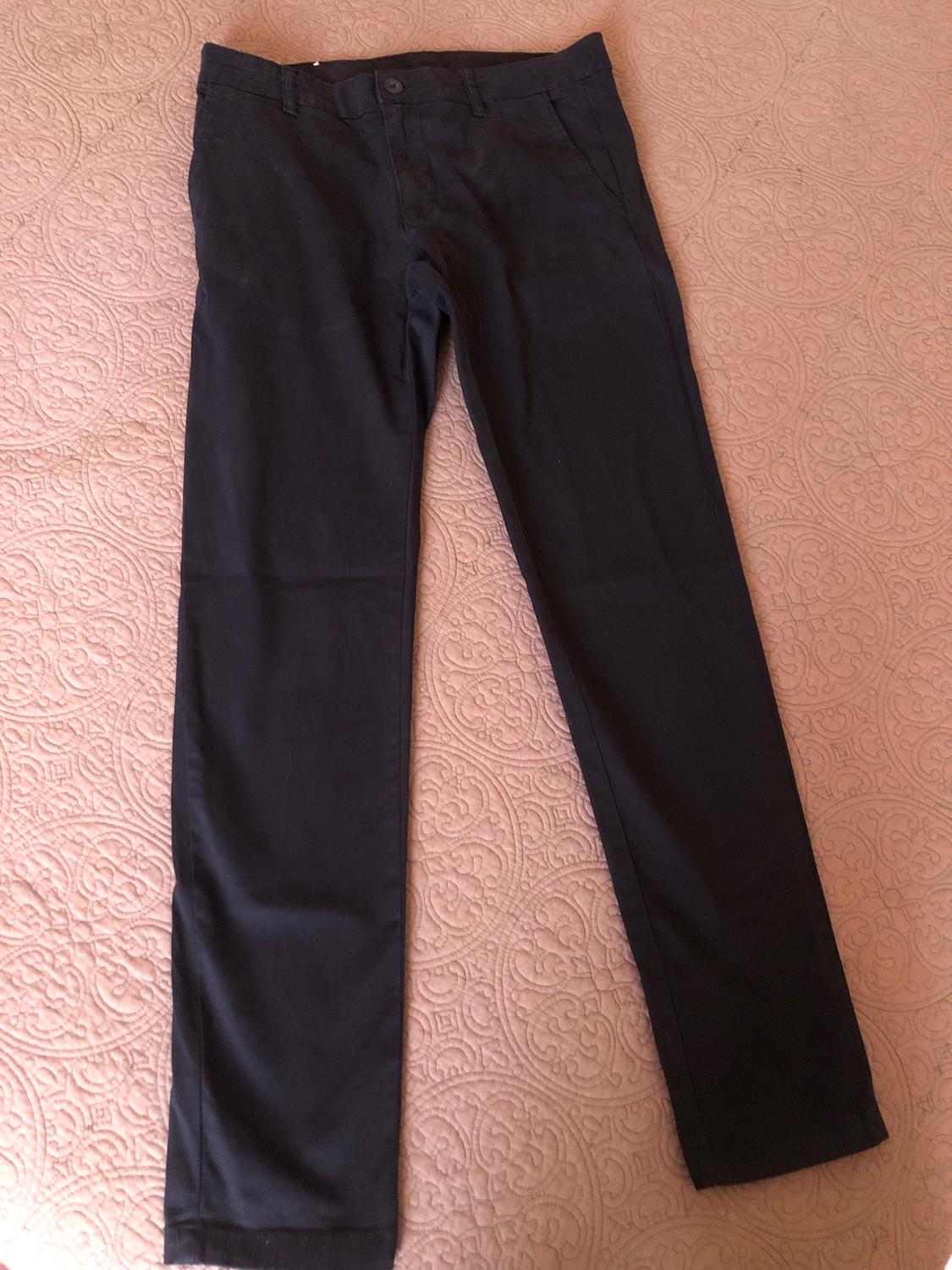 Black dress trousers on a bedspread with an embossed circular pattern design.