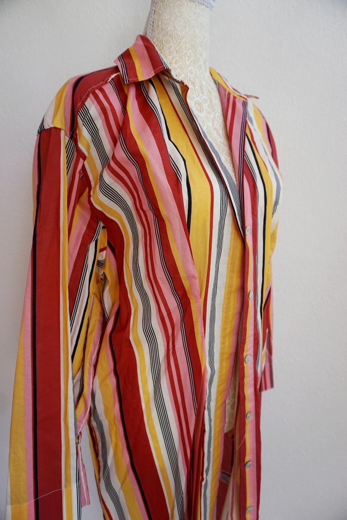 Vertical striped shirt in red, yellow, pink, and black on a white mannequin. Plain white background.