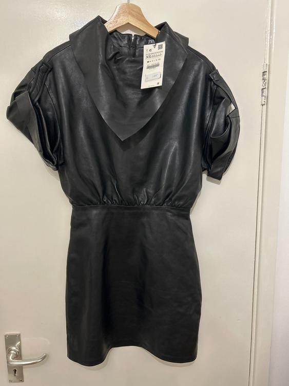 Black short-sleeved dress hanging on a wooden hanger, with a visible label indicating size XS and a price of 149.