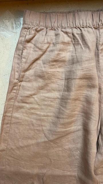 Beige linen trousers with elasticated waistband and side pockets, on a light background.