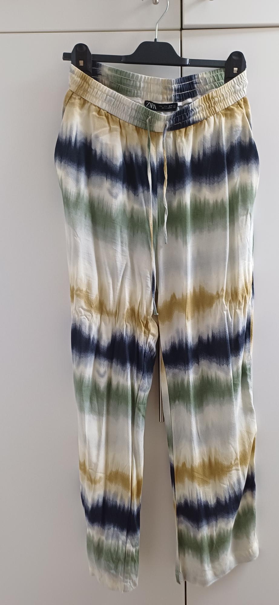 Hanging trousers with a striped print in shades of blue, green, and beige. Elasticated waist with adjustable drawstring.