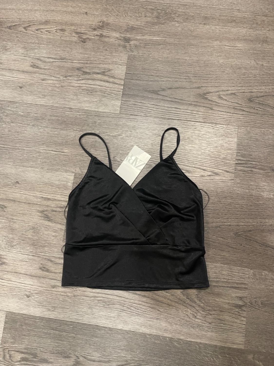 Front view of a black top with thin straps and a crossover neckline.