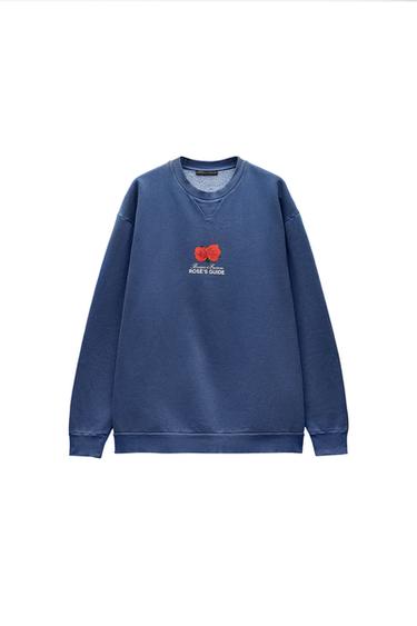 Front view of a blue sweatshirt with a rose print and the text 'Roses Guide' on the chest.