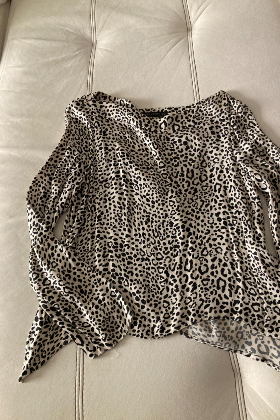 Front view of a blouse with an animal print in black and beige tones, with long sleeves.