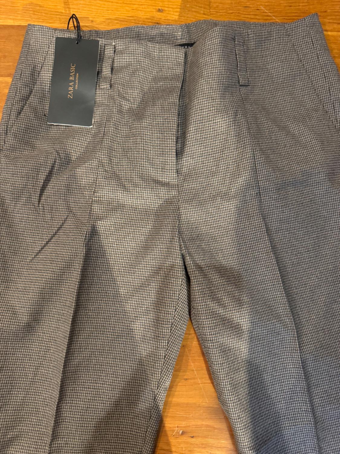 Detail of checked trousers with side pockets and 'ZARA BASIC' label.