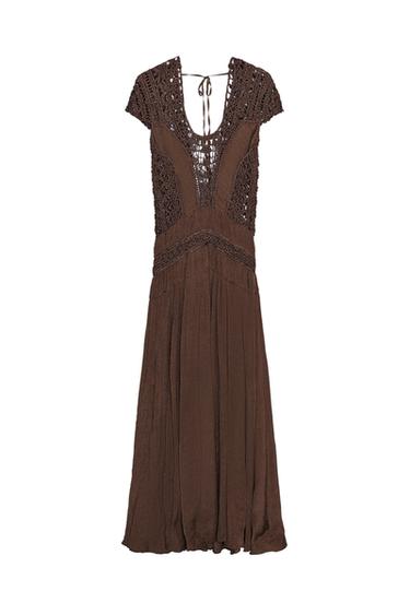 Front view of a chocolate brown dress with a round neckline, short sleeves, and crochet detailing. Back fastening with ties.
