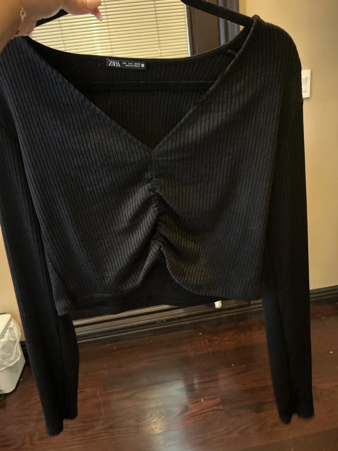 Front view of a black long-sleeved top with a central ruched detail and a V-neck.