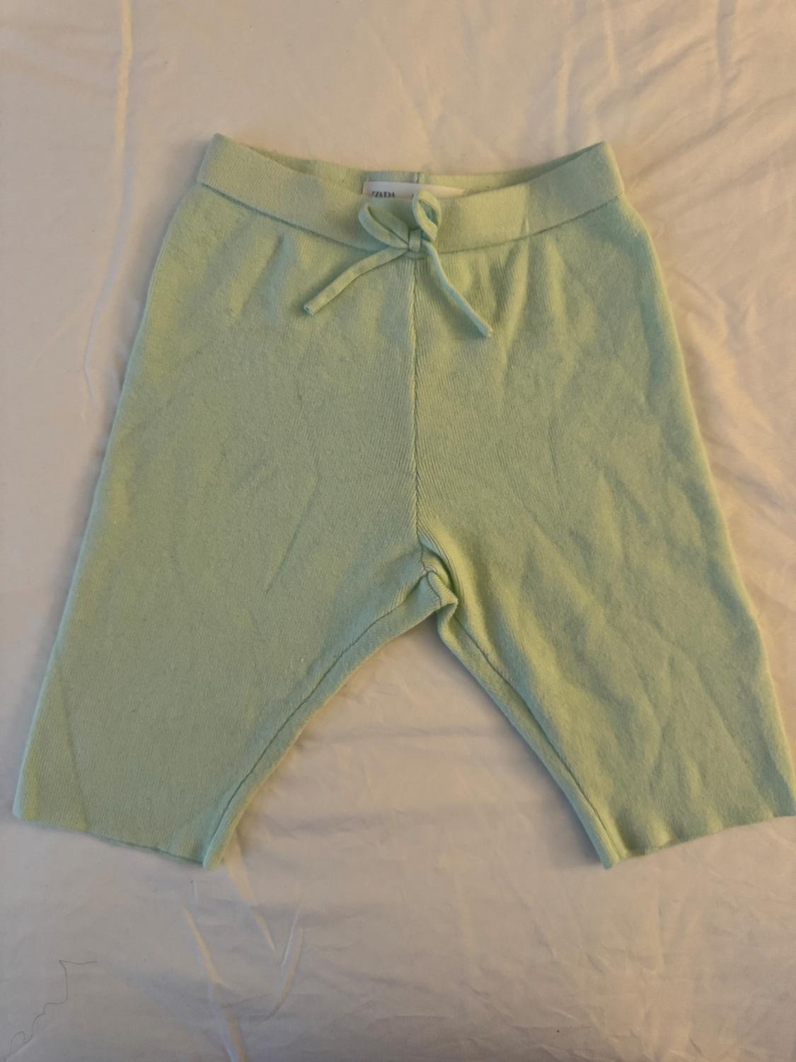 Front view of green shorts with elastic waistband and decorative tie.