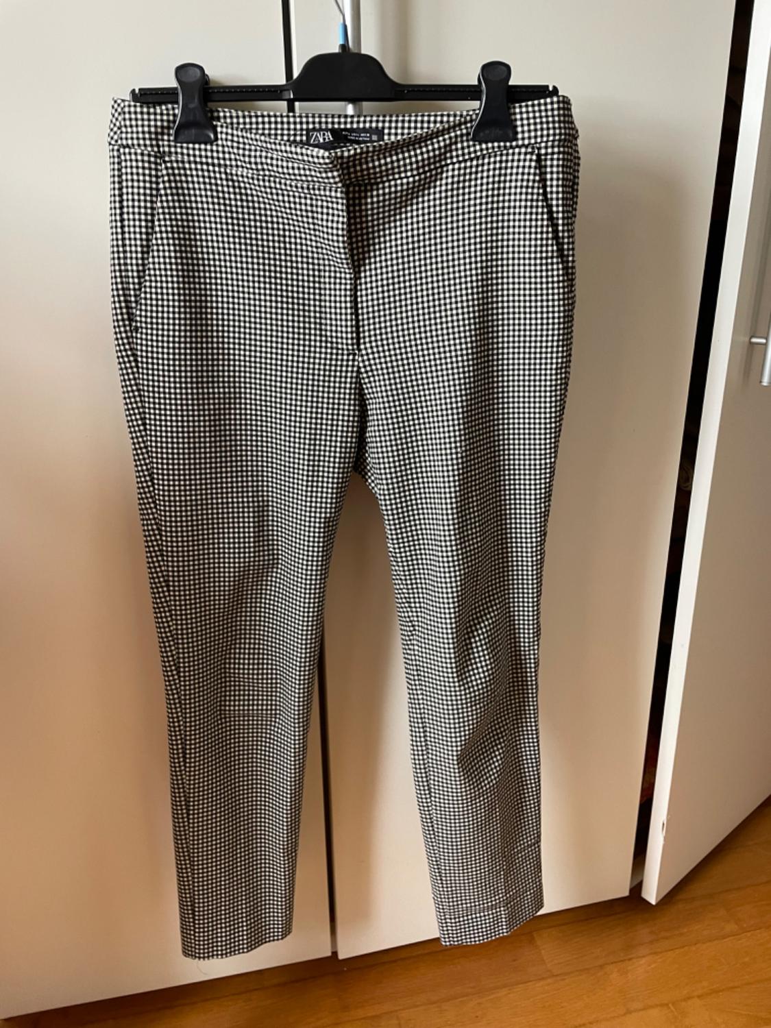Front view of black and white checked trousers with side pockets.