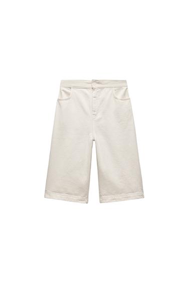 Front view of beige Bermuda shorts with front pockets and button fastening.