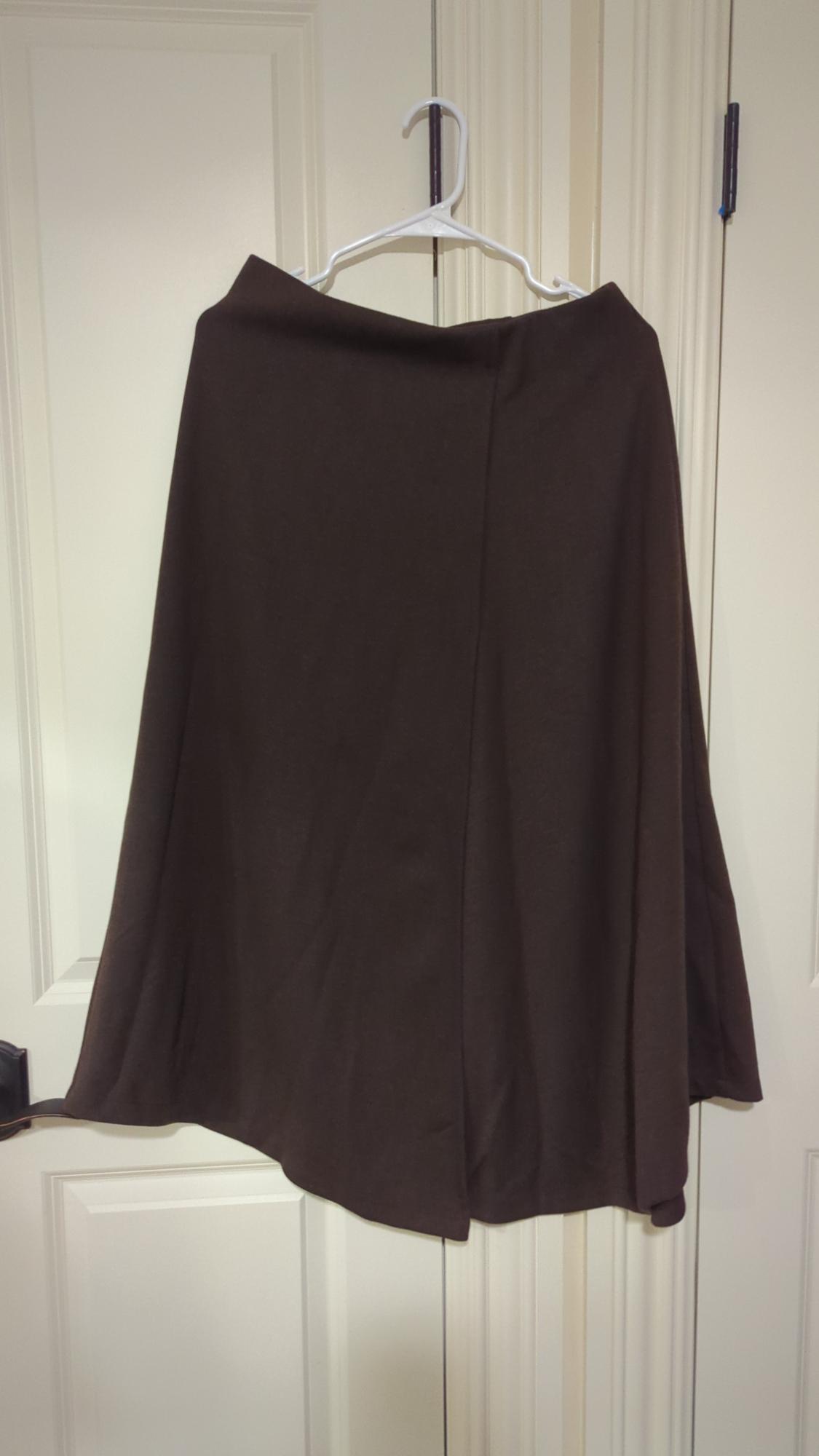 Brown skirt hanging on a white hanger over a white door. The fabric appears light and flowing.