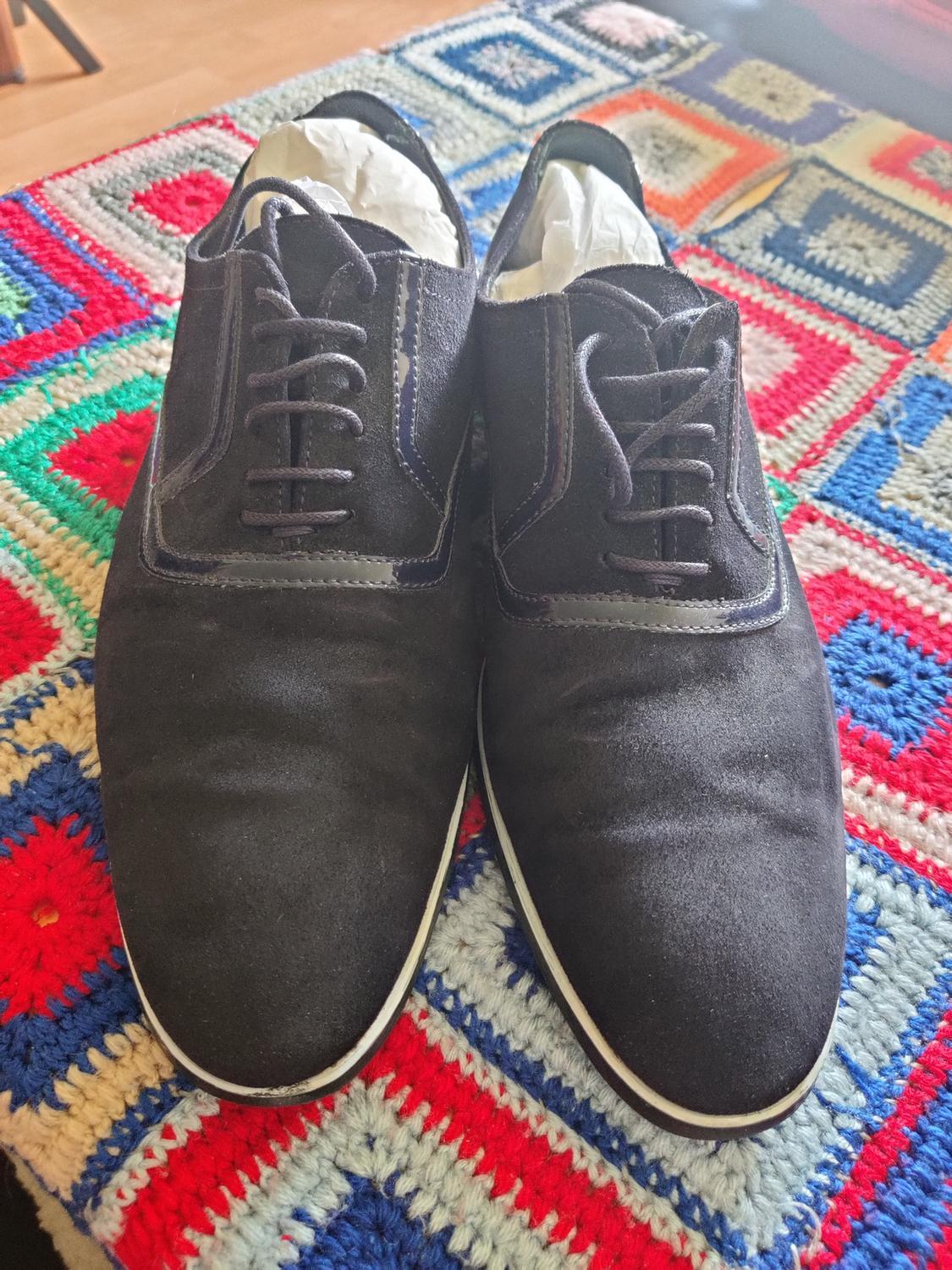 Front view of black lace-up shoes on a colourful rug