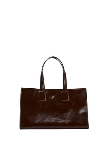 Dark brown handbag with slender handles, on a white background. Minimalist and elegant design.
