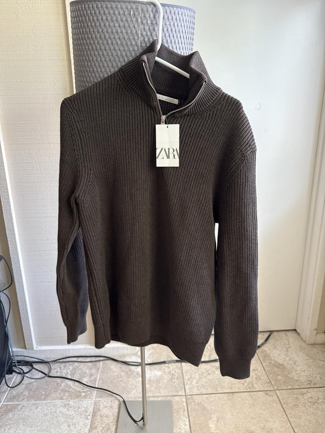 Dark brown ribbed jumper with a half-zip, hanging on a hanger indoors. Label with the text ZARA.