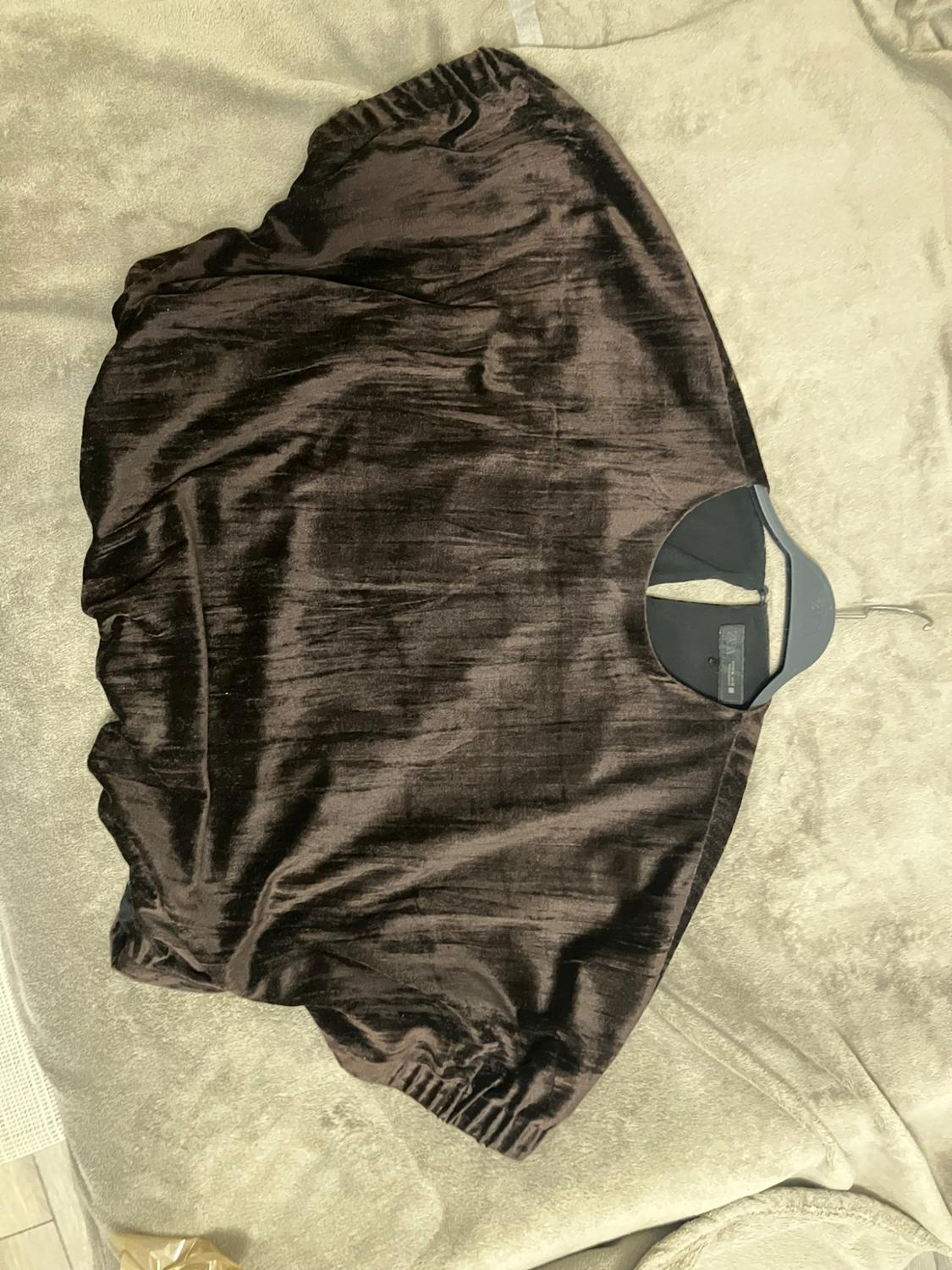Dark brown gloss-finish short-sleeve top with a crew neck, on a hanger over a light-coloured blanket.
