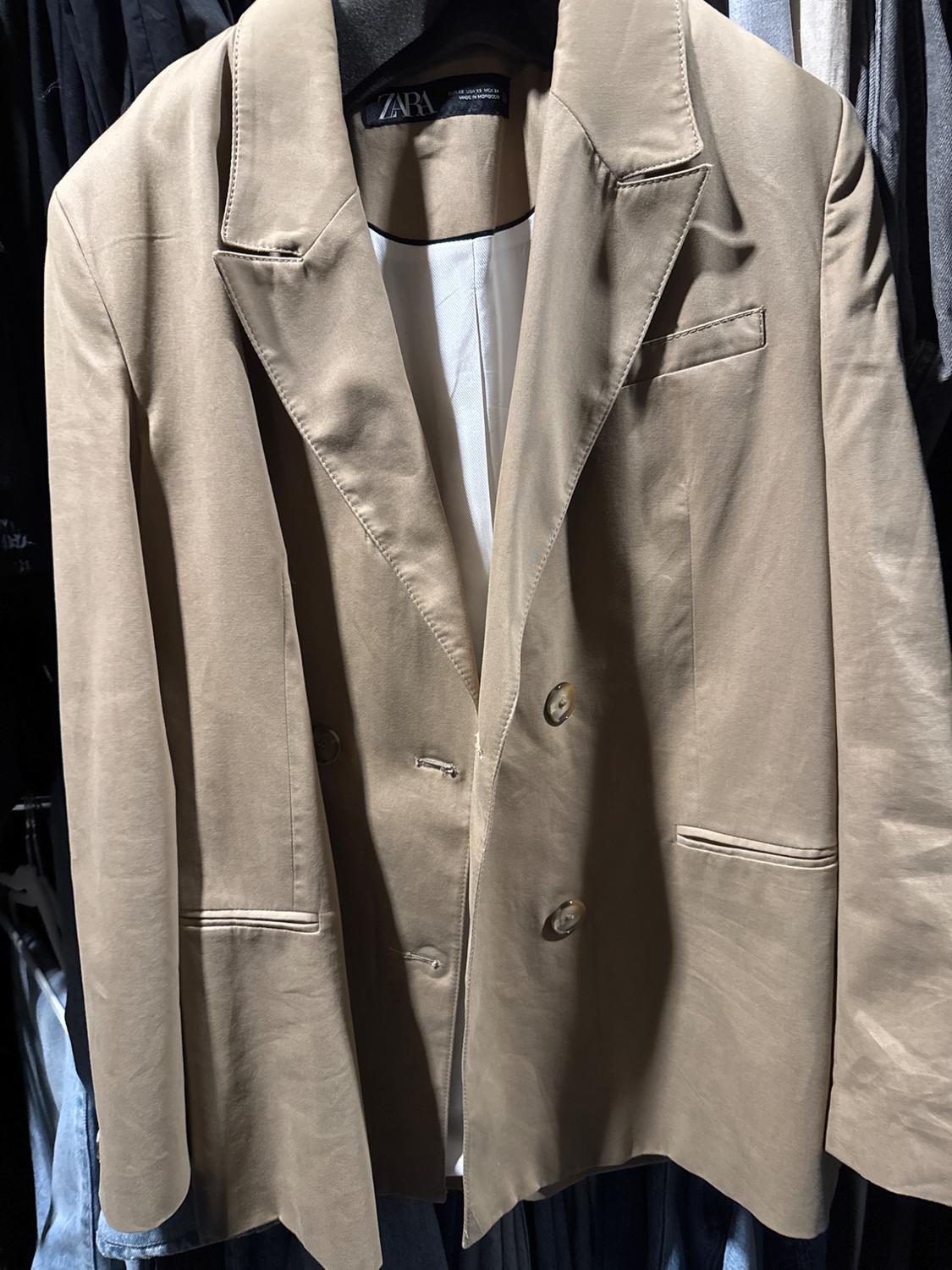 Front view of a beige jacket with lapels and side pockets.