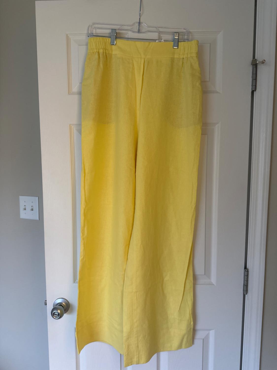 Front view of yellow trousers with an elasticated waistband and a straight cut, hanging on a hanger.