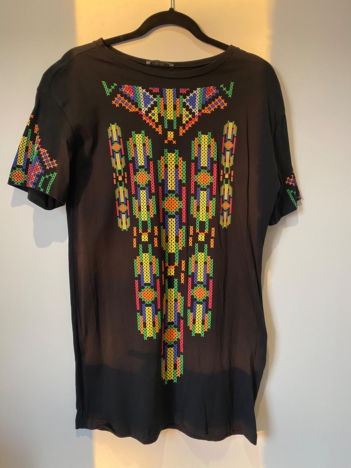 Front view of black t-shirt with multicoloured geometric print on the chest and short sleeves.