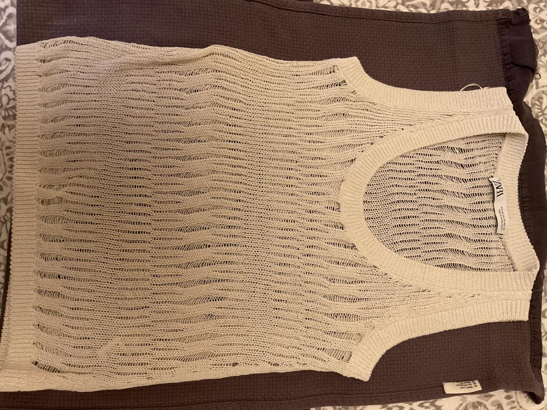 Beige sleeveless open-knit top with a wide neckline and wavy texture, over dark brown fabric. Label with the text ZARA.