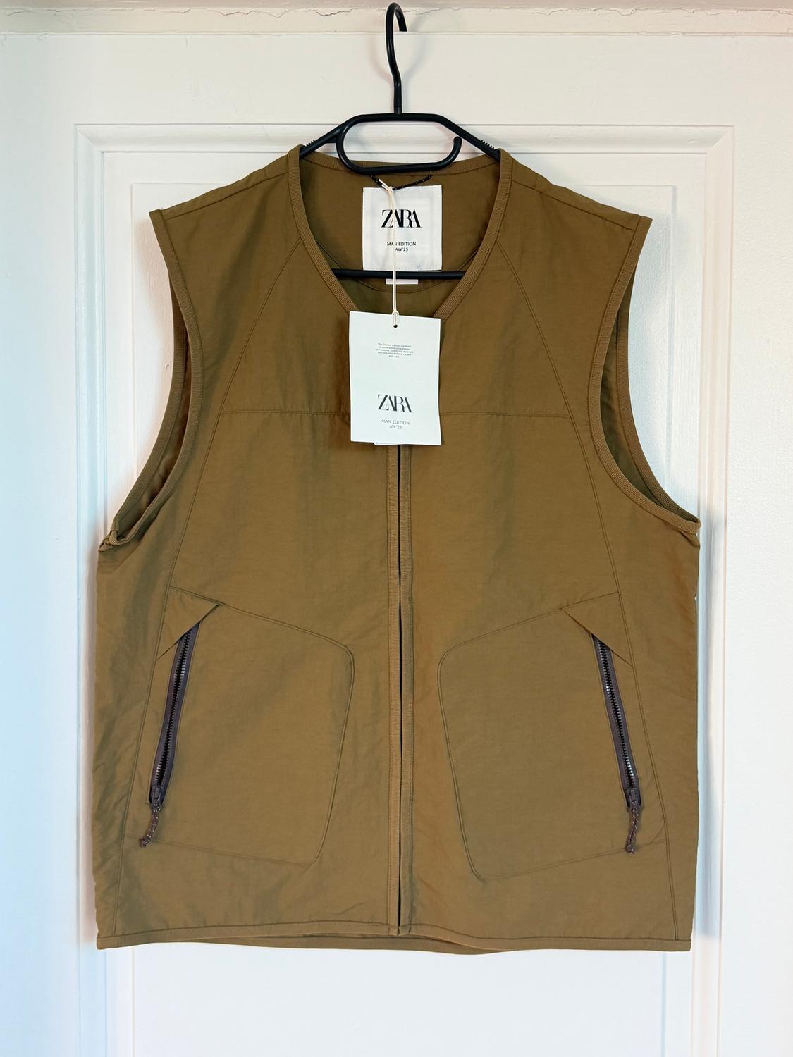 Khaki sleeveless gilet with front zip fastening and zip pockets. Visible label with the text "ZARA".