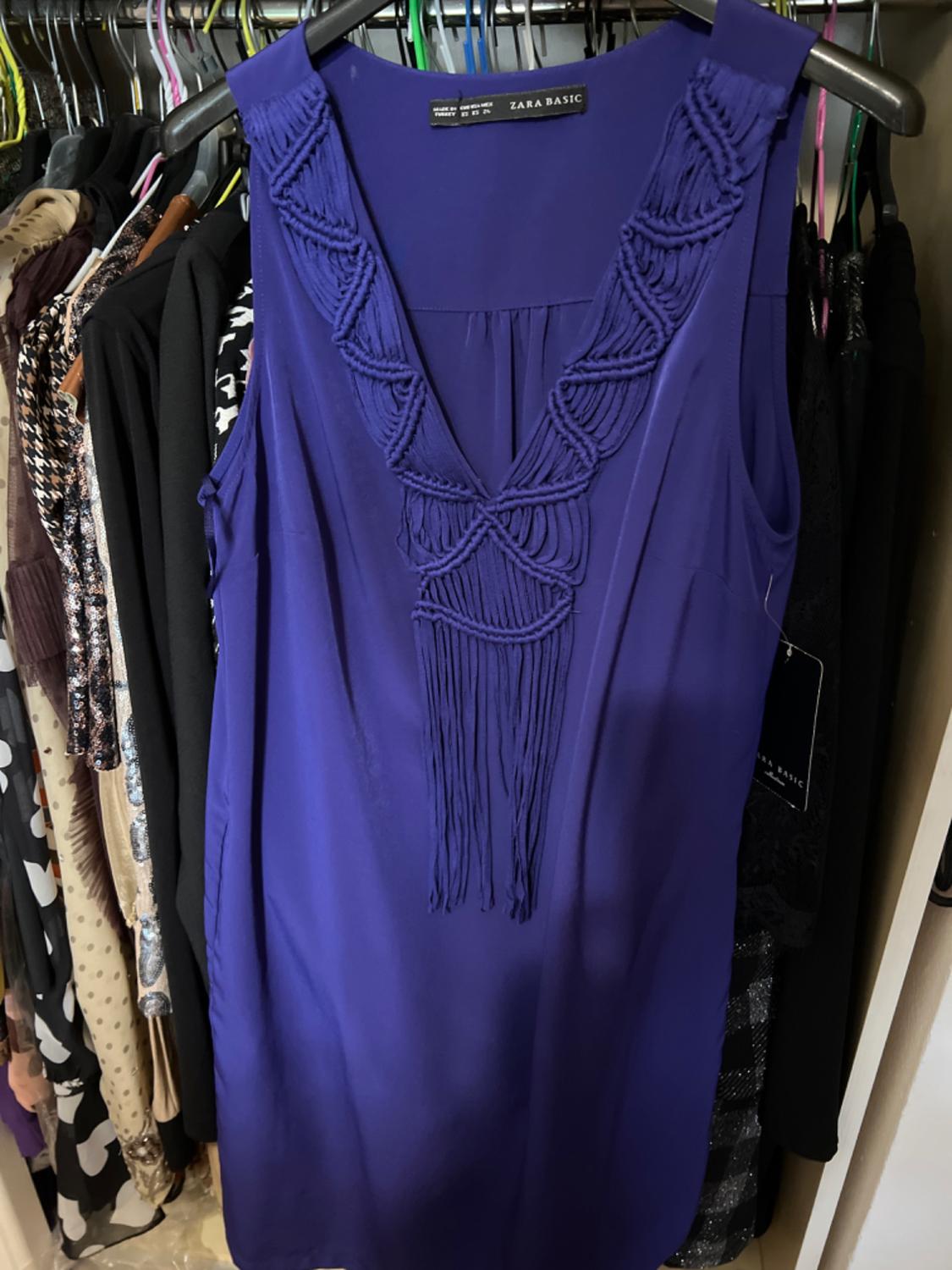 Front view of a blue dress with a V-neck and braided details at the neckline.