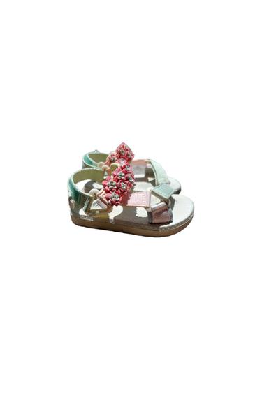 Children's pastel green, pink, and white strappy sandals, with pink floral appliqués on the instep, on a white background.