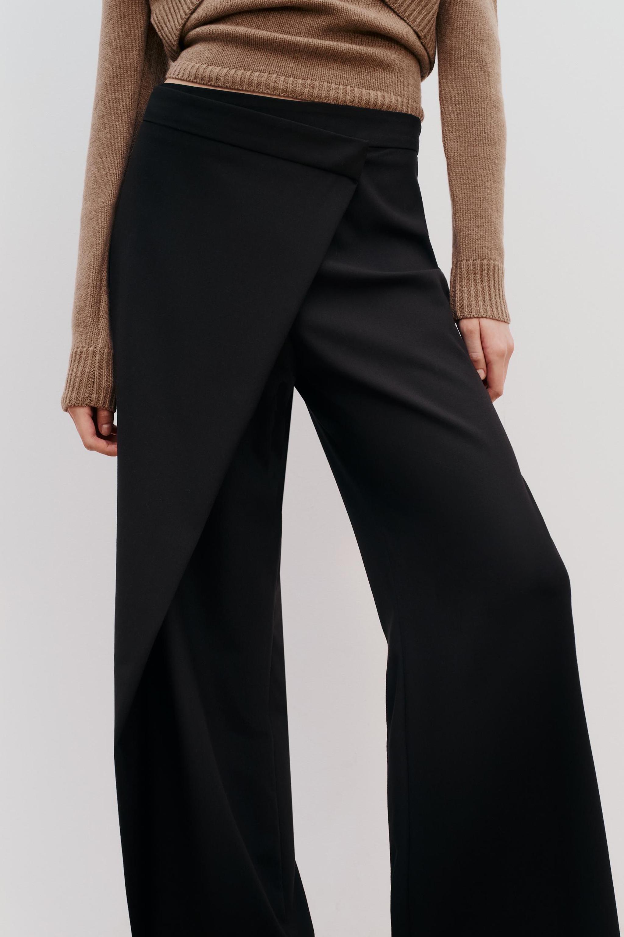 Pants with a high front wrap waist and snap button. Wide leg. Side hidden  in-seam zip closure. - Black