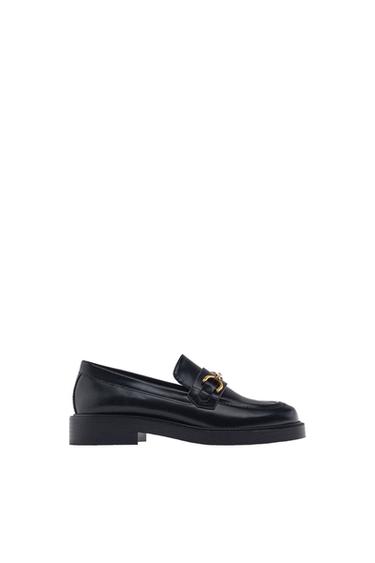 Side view of a black loafer with a gold buckle detail.