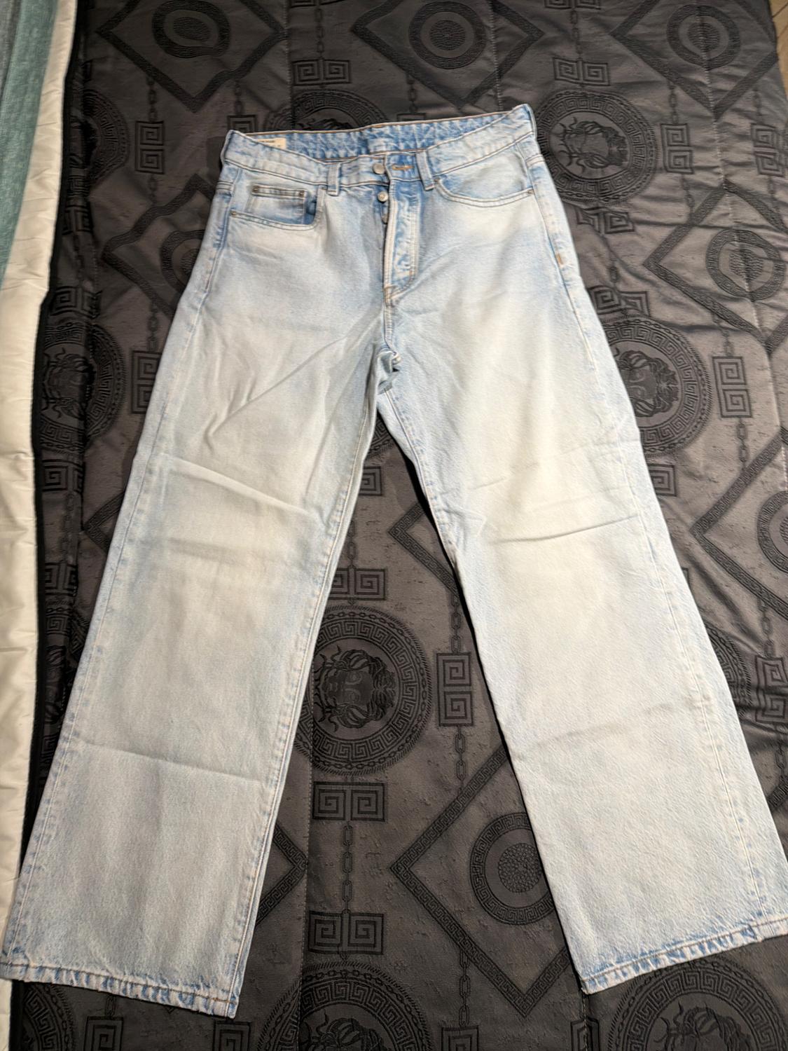 Light-wash straight-leg jeans on a quilt with a geometric design in dark tones.