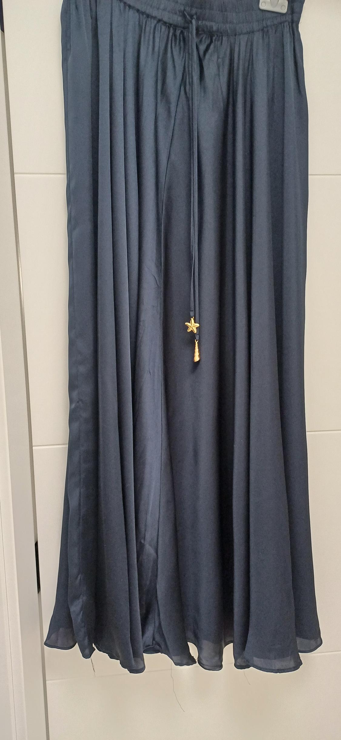 Dark blue hanging skirt, with pleats and an adjustable drawstring adorned with a gold star and tassel. White background.
