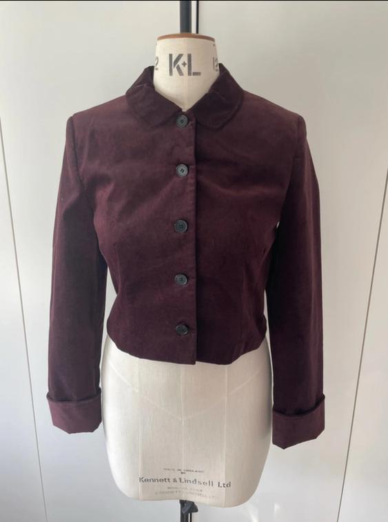 Mannequin with a short, burgundy velvet jacket, black buttons, and a round neck. Visible text: "Kennett & Lindsell Ltd".