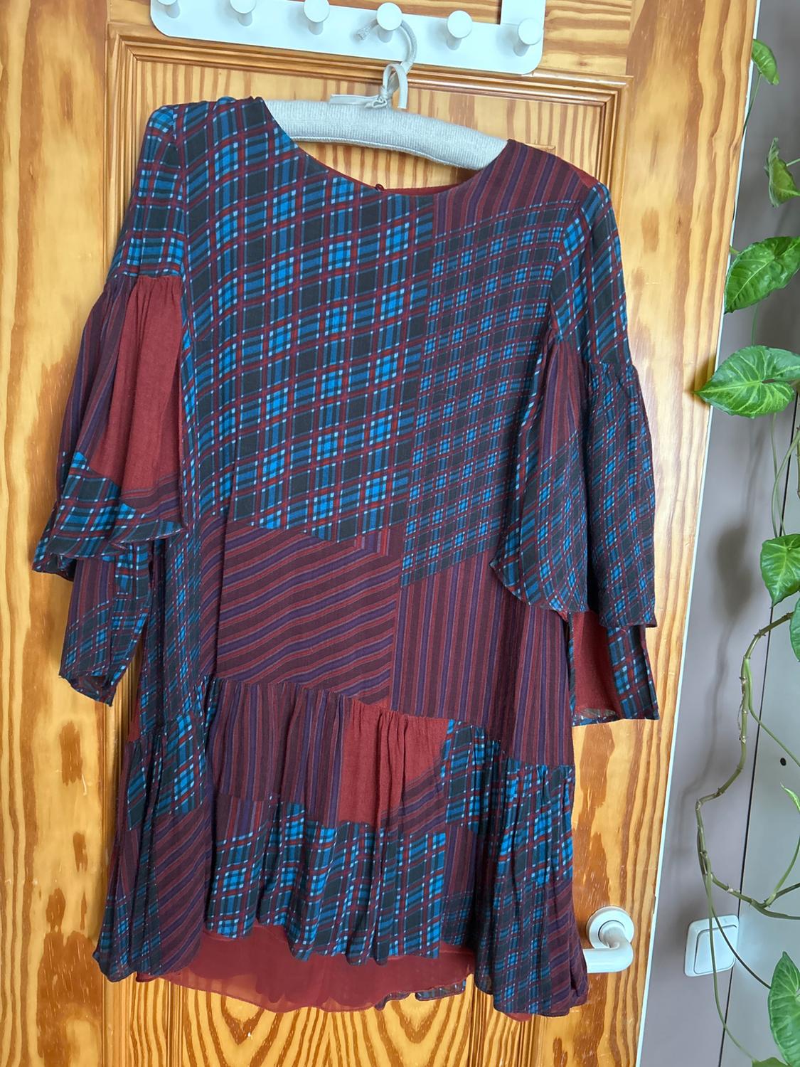 Front view of a red and blue checked dress with frills and wide sleeves.