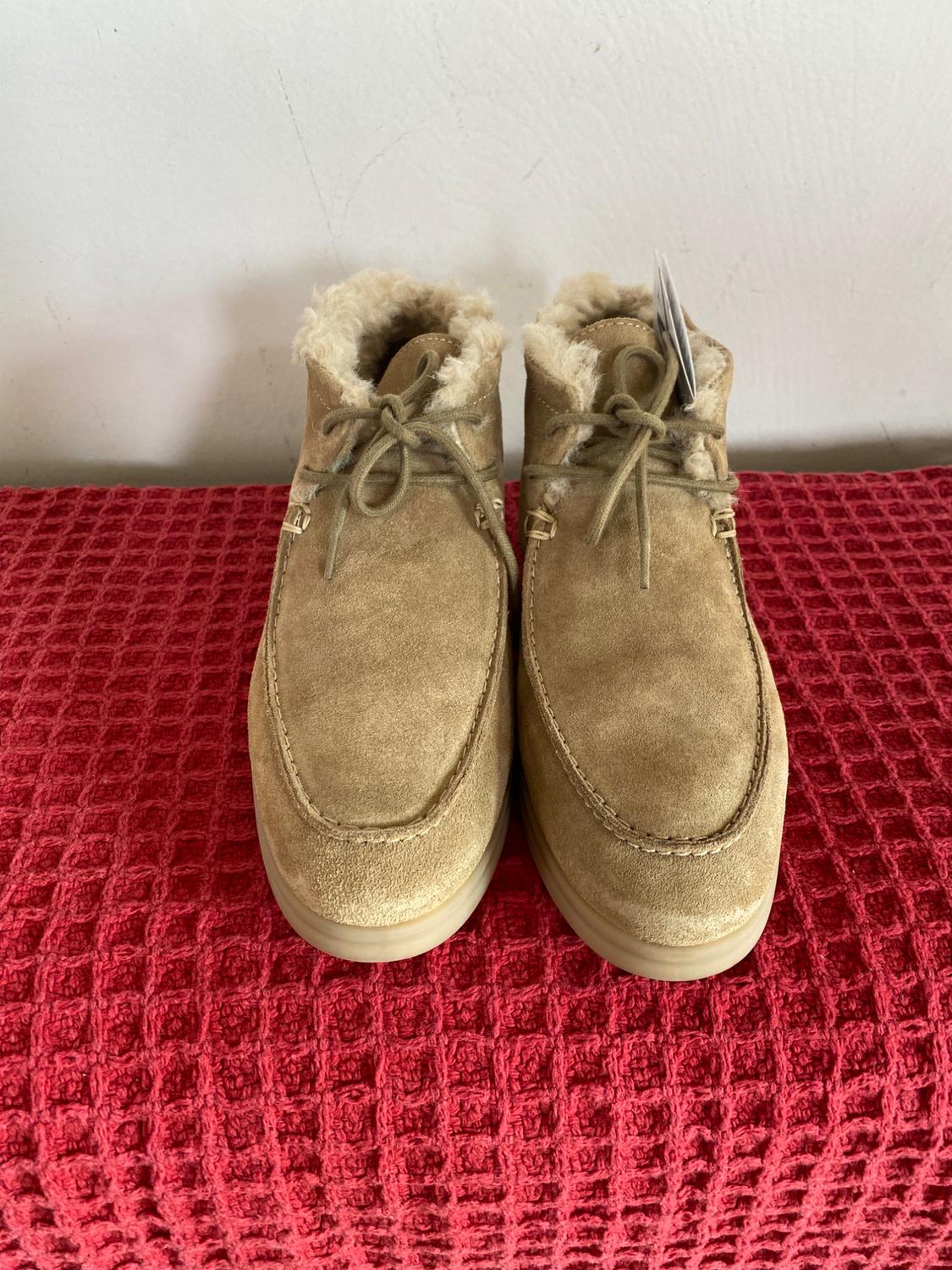 Beige suede boots with plush lining and laces, on a red blanket with a checkered texture.