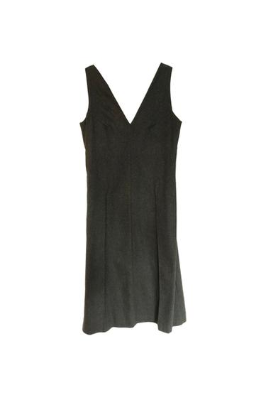 Sleeveless black dress with a V-neck, hanging on a white background. Simple and elegant design.