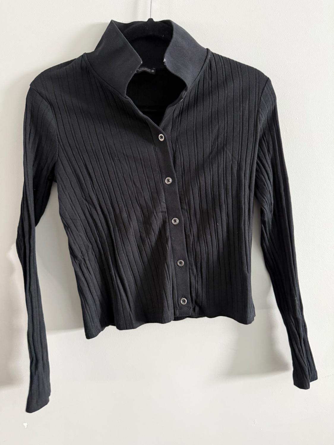 Long-sleeved black shirt with ribbed texture and front buttons, hanging on a white background.