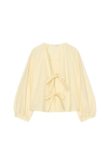 Front view of a yellow blouse with front ties and puff sleeves.
