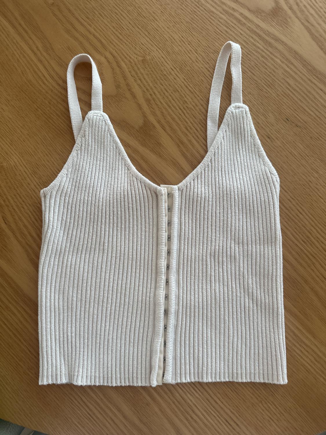 White ribbed camisole top on a light wooden surface.
