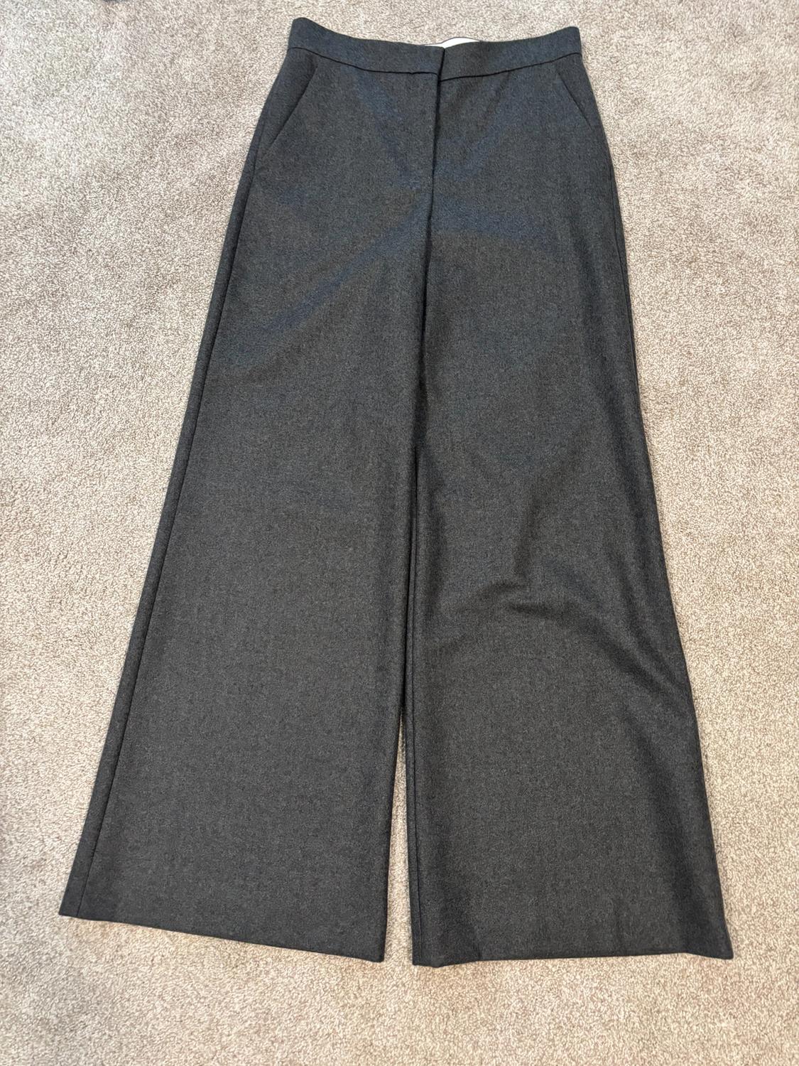 Gray wide-leg pants made of thick fabric on a beige carpet, with side pockets and a high waist.