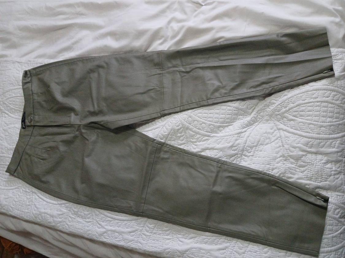 Light grey trousers laid out on a white textured bedspread.