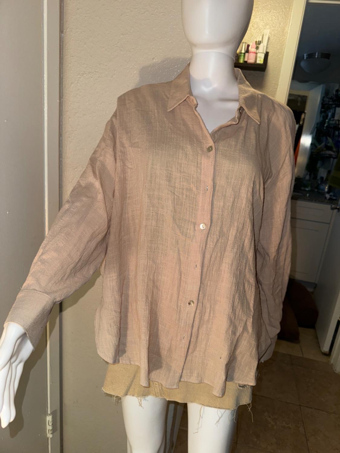 Long-sleeved beige button-up shirt with a classic collar, on a mannequin.