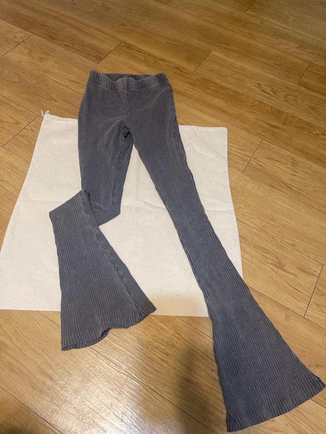 Gray corduroy flare pants on a light wooden background with white fabric.