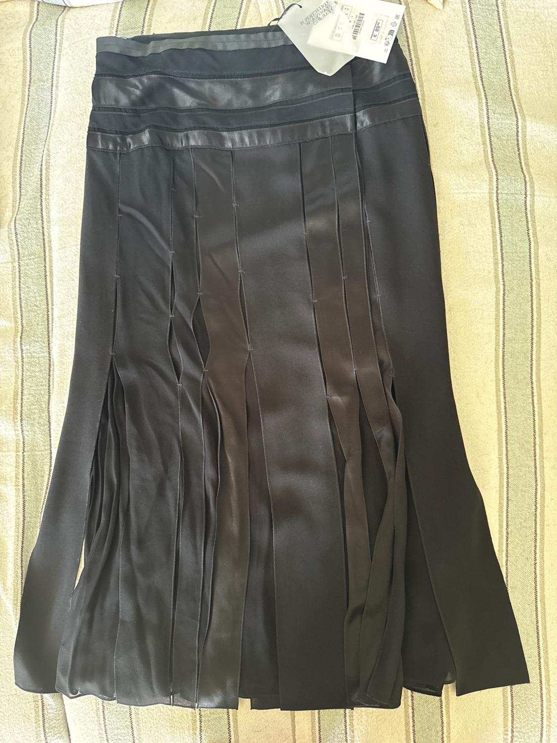 Black skirt on a striped background, with horizontal bands and loose vertical panels. Label: ZARA WOMAN COLLECTION.
