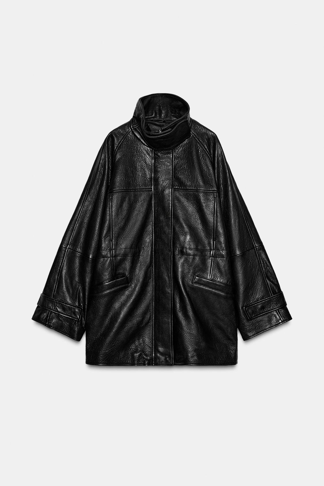 Front view of black jacket with high neck, long sleeves with tab, jetted pockets and concealed front fastening.