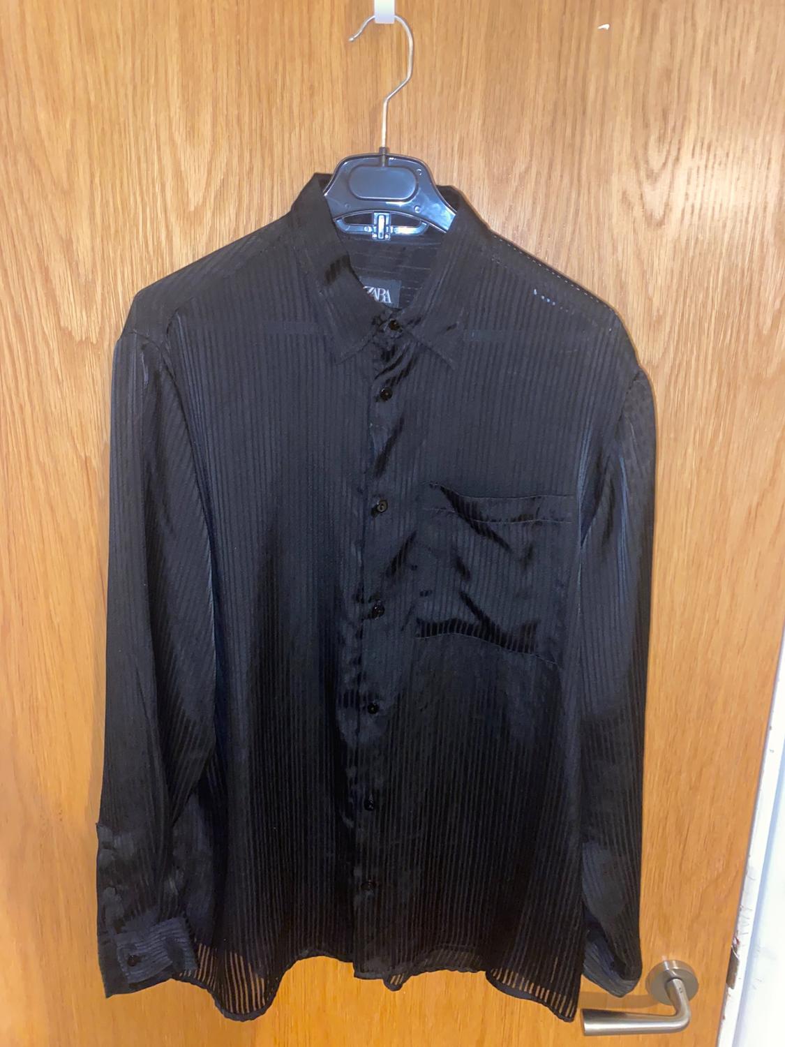 Front view of black button-front shirt with chest pocket.