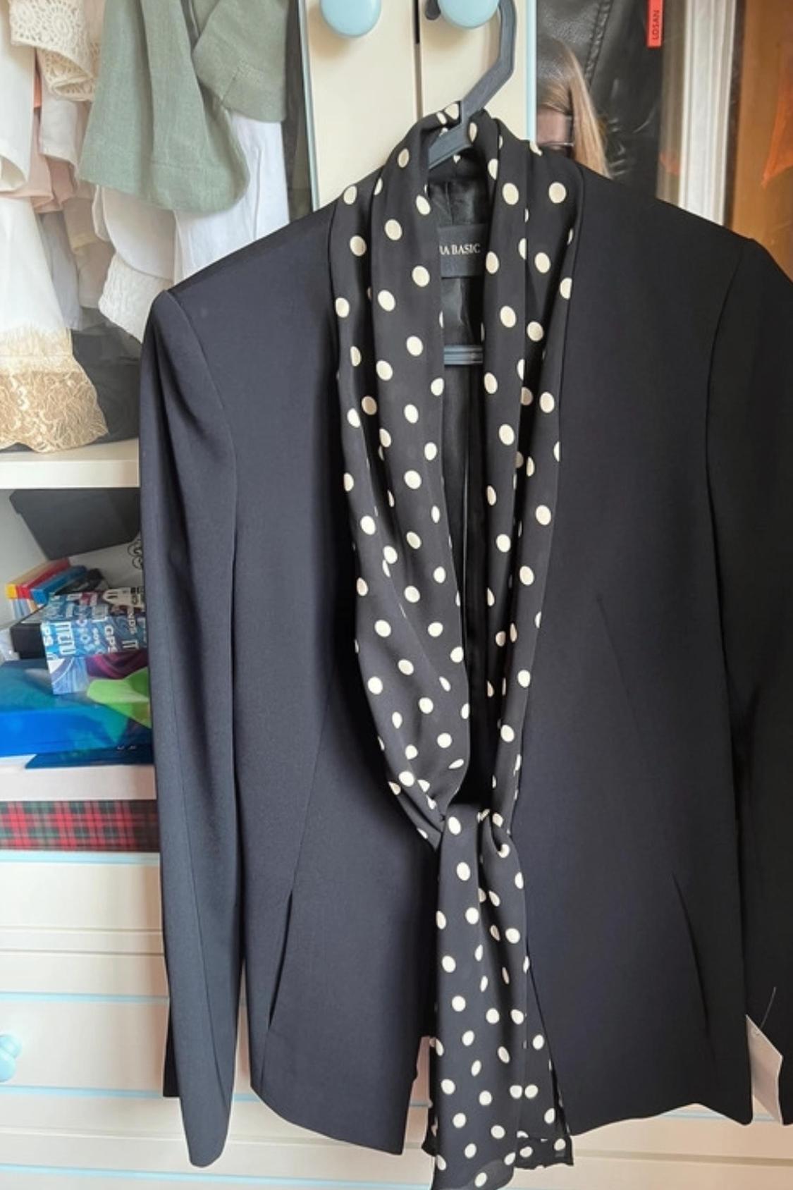Front view of black jacket with white polka dot scarf.